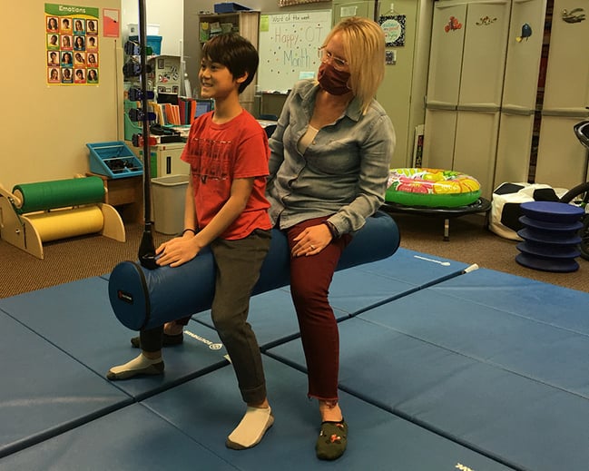 Child and Occupational Therapist on a piece of therapy equipment