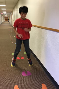 Child hopping on painted footsteps on floor for occupational therapy
