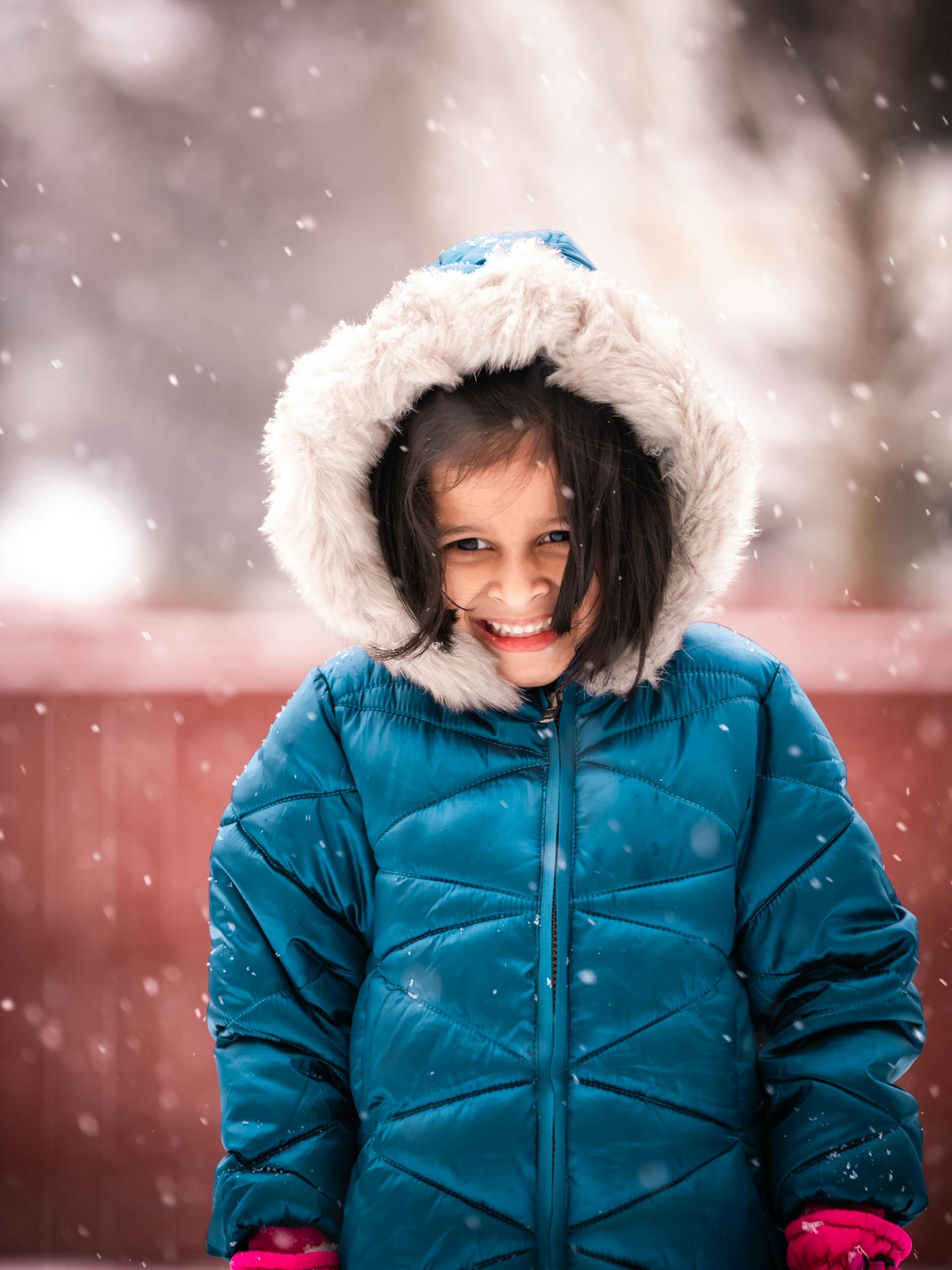 Photo of smiling child wearing a winter coat in the snow by Gigin Krishnan on Unsplash 